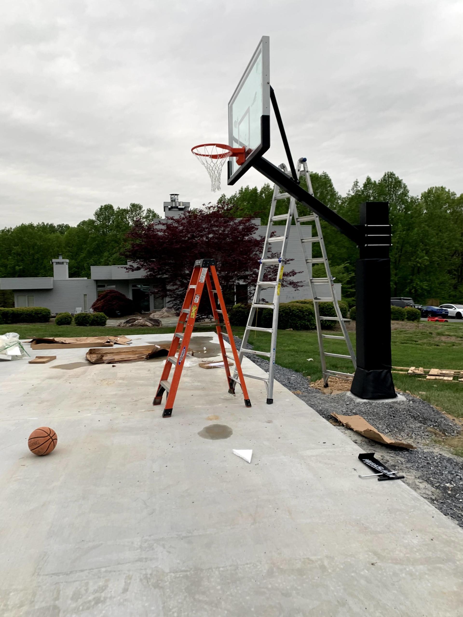 A basketball is sitting on the ground next to a basketball hoop.