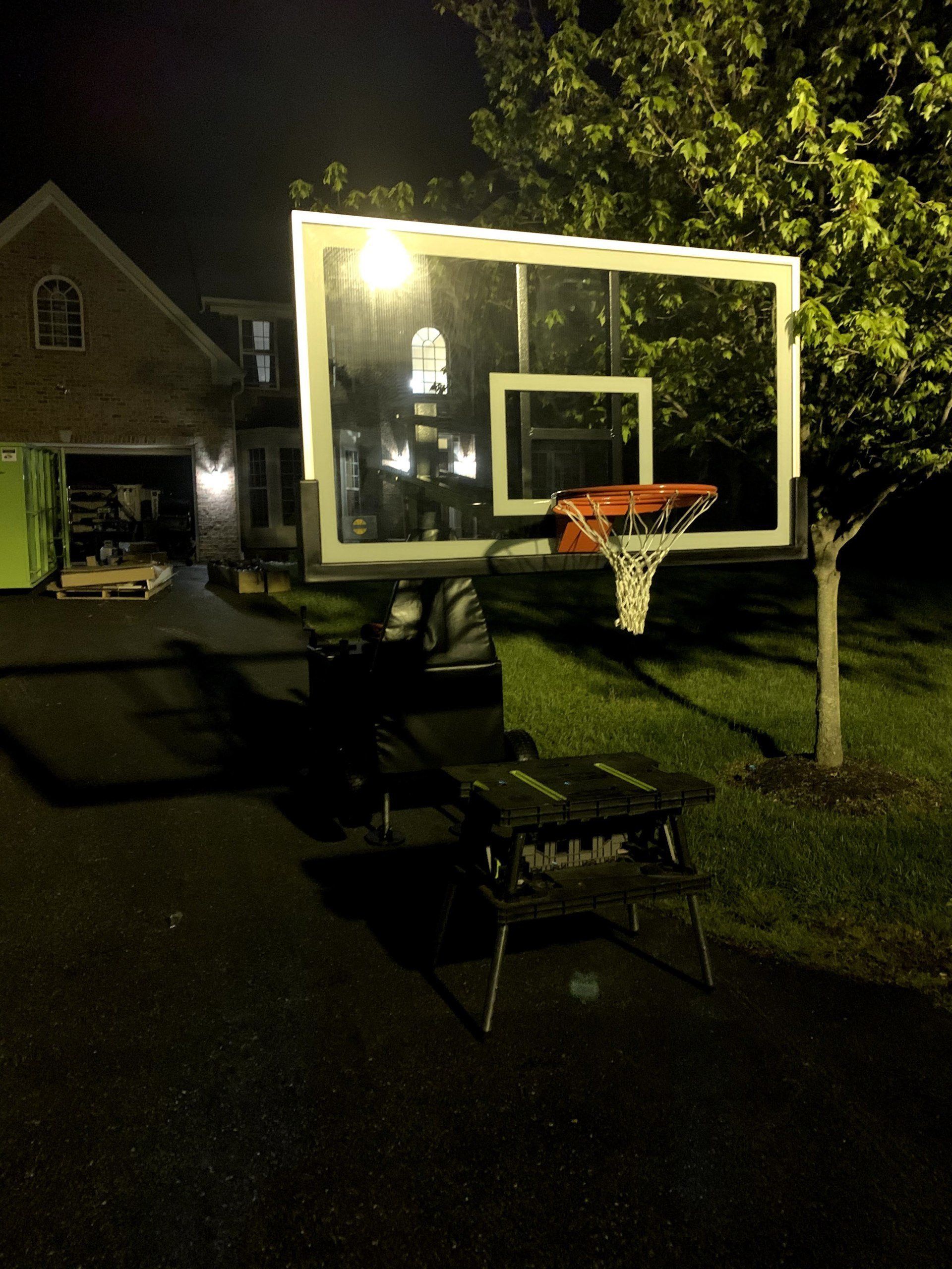 A basketball hoop sits in front of a house at night