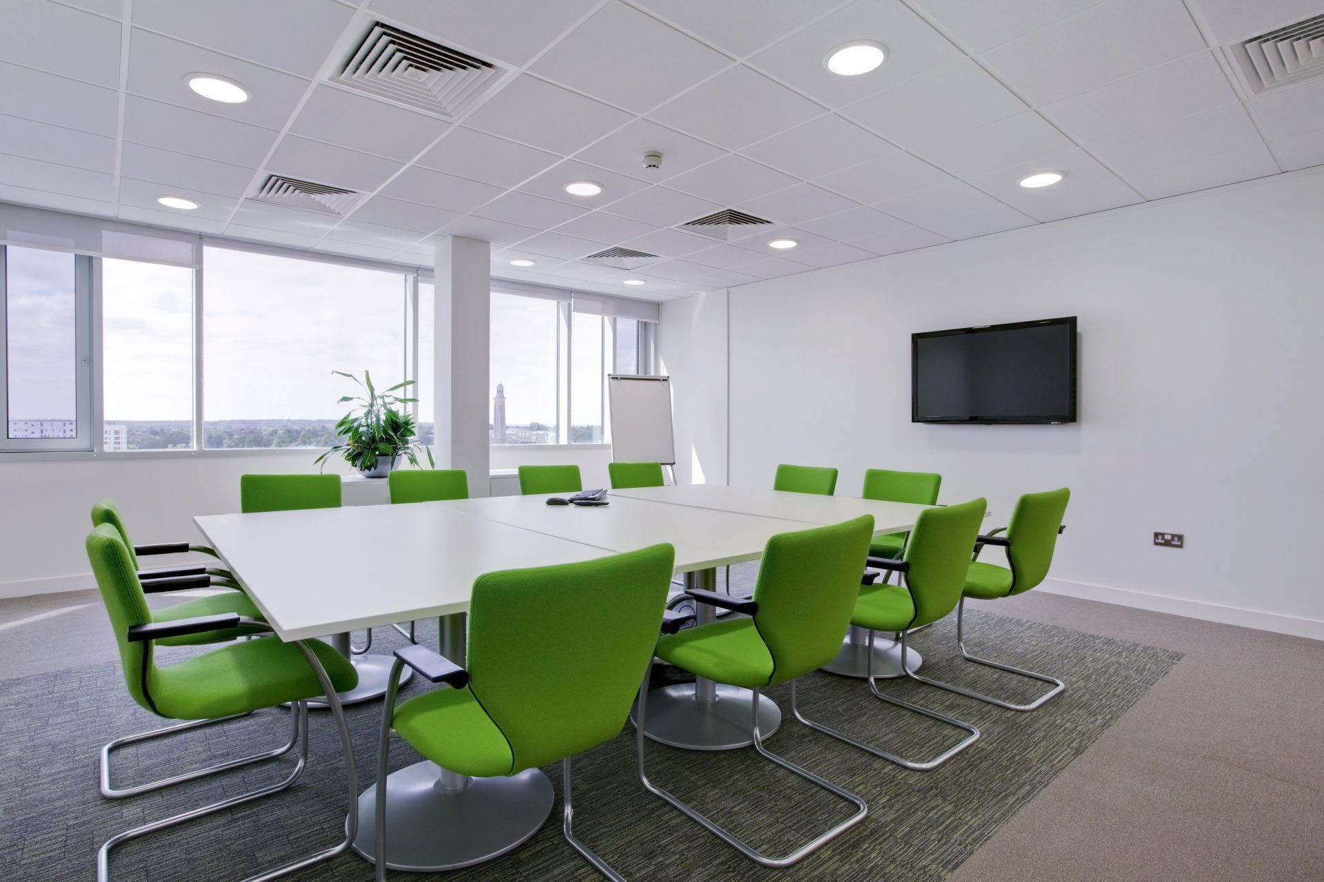 A conference room with a long table and green chairs.