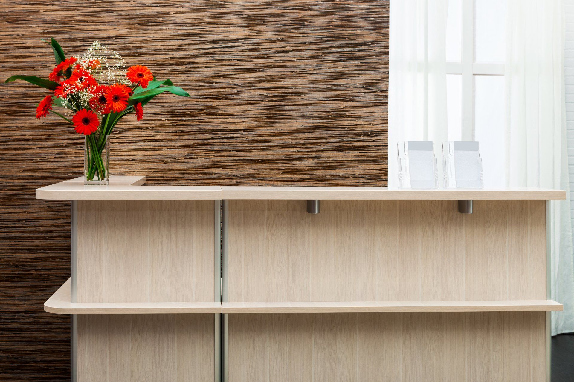 A reception desk with a vase of flowers on it.