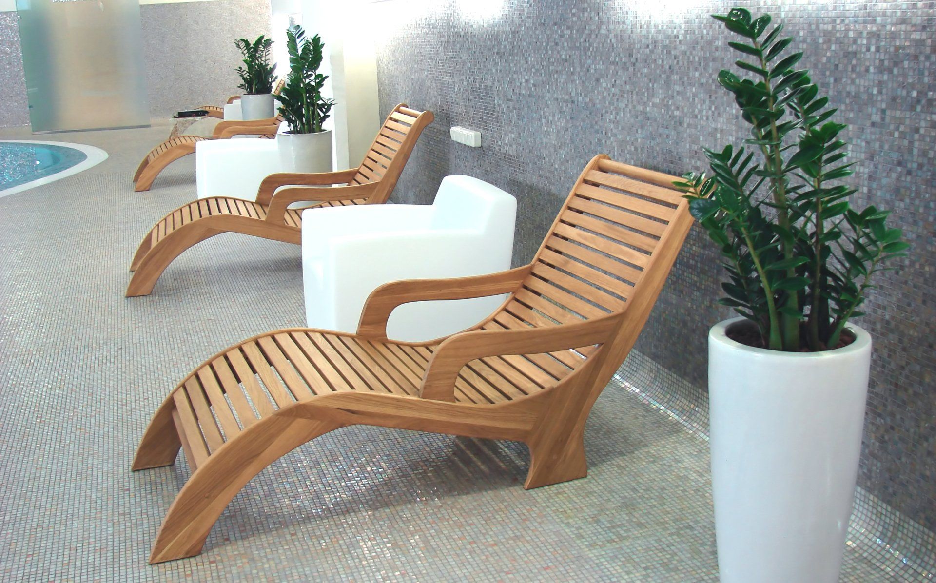 A row of wooden lounge chairs next to a potted plant
