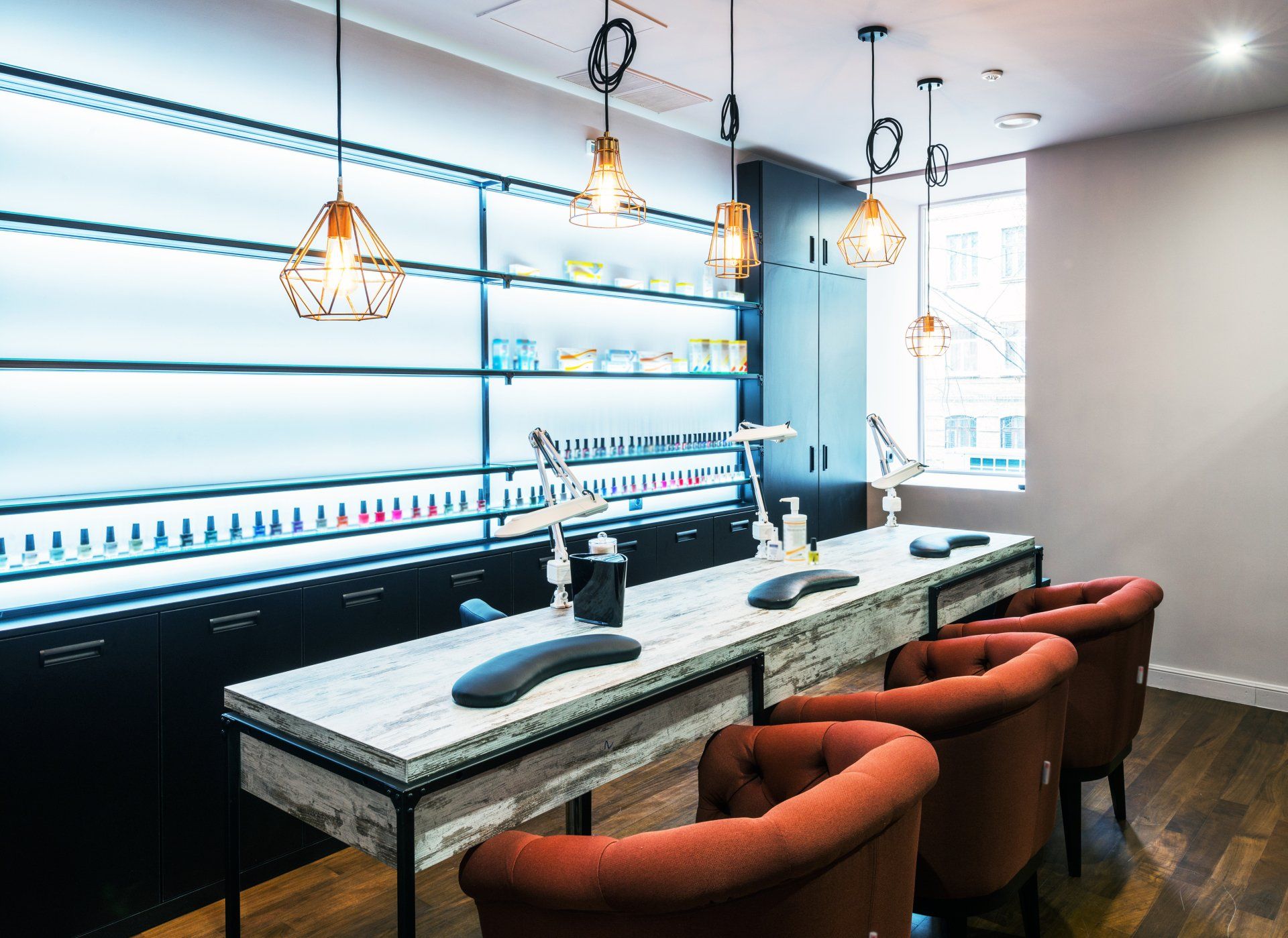 A room with a long table and chairs in a nail salon.