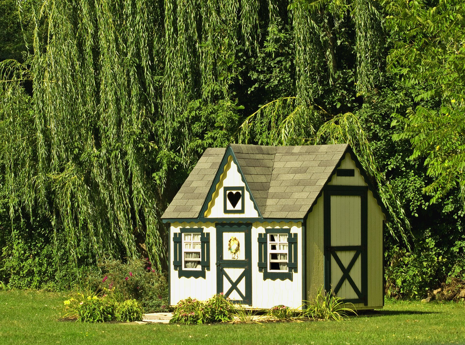 A small white and black playhouse in the middle of a grassy field