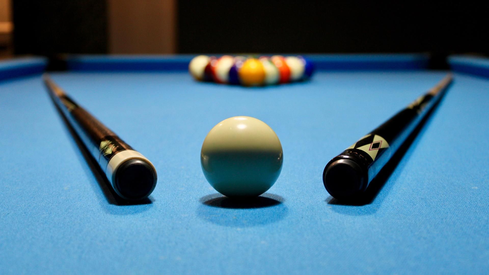 A pool table with two cues and a ball on it