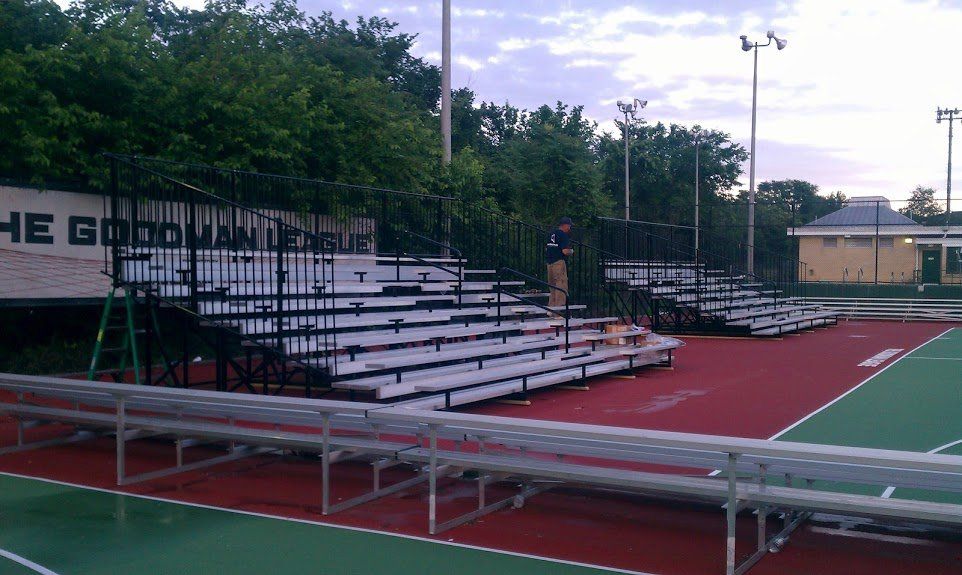 A tennis court with bleachers and a sign that says the good and unique