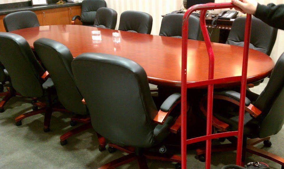 A red hand truck is being used to move a conference table