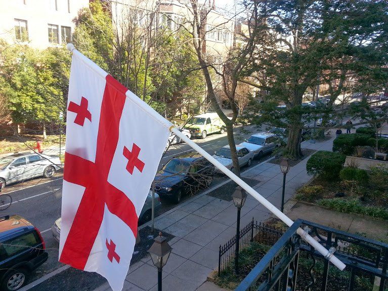 A georgian flag is hanging from a pole on a balcony