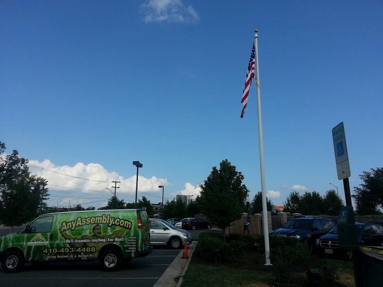 A green van is parked in front of an american flag