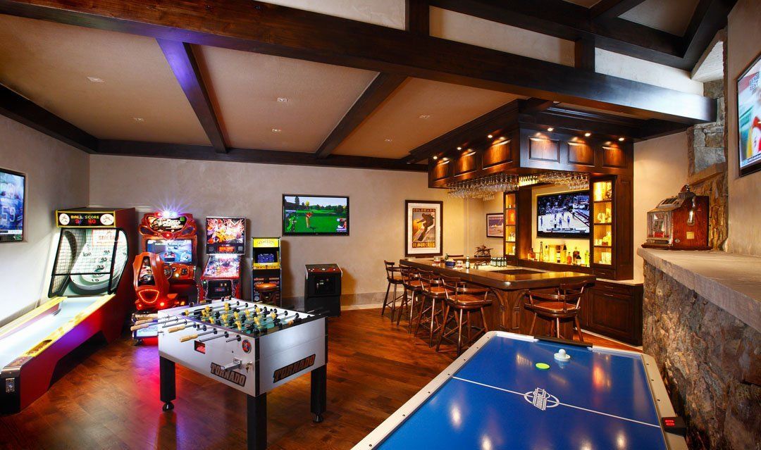 Game room with arcade games, foosball, air hockey, bar, and TVs.