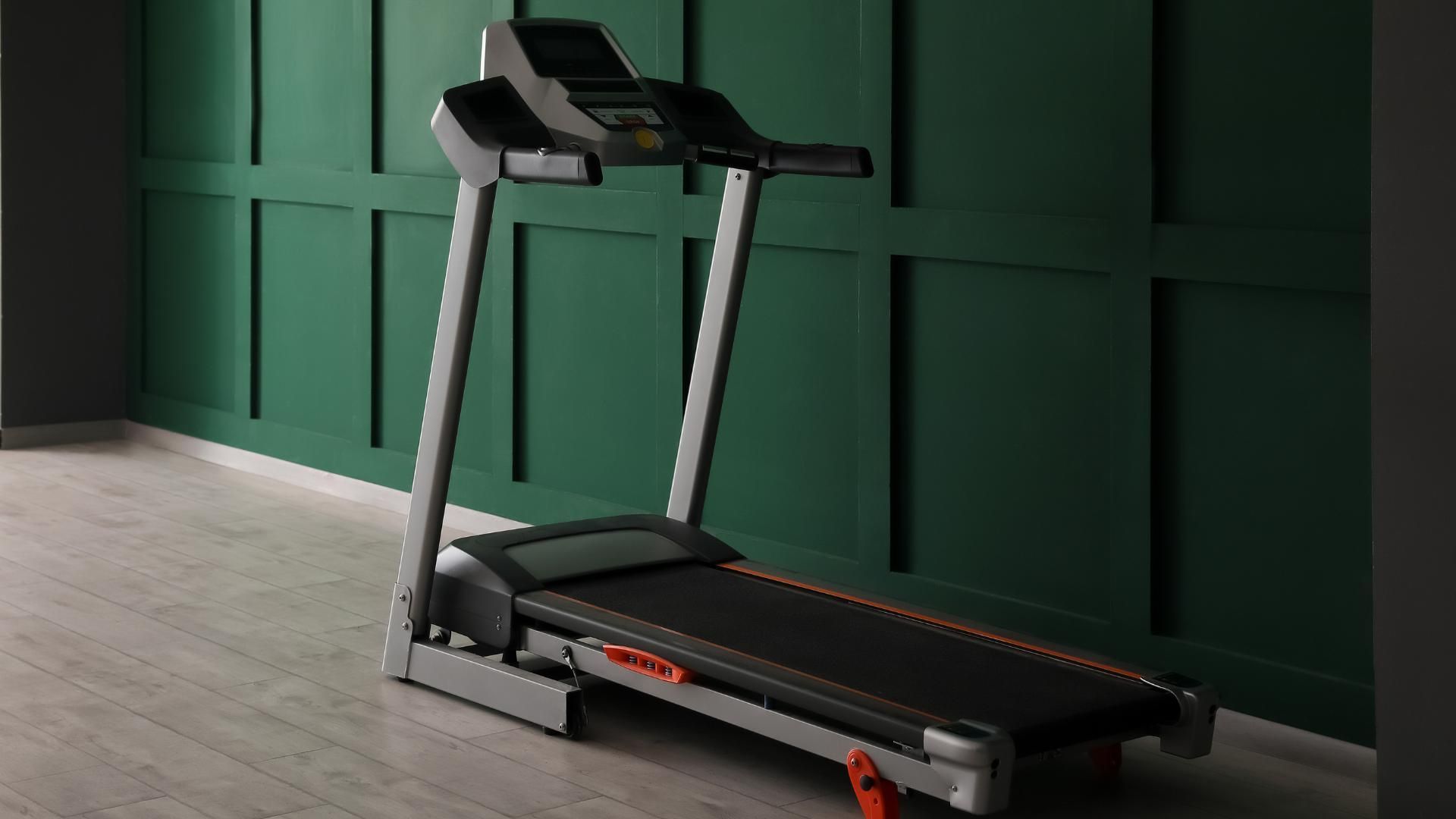 A treadmill is sitting in a room next to a green wall.