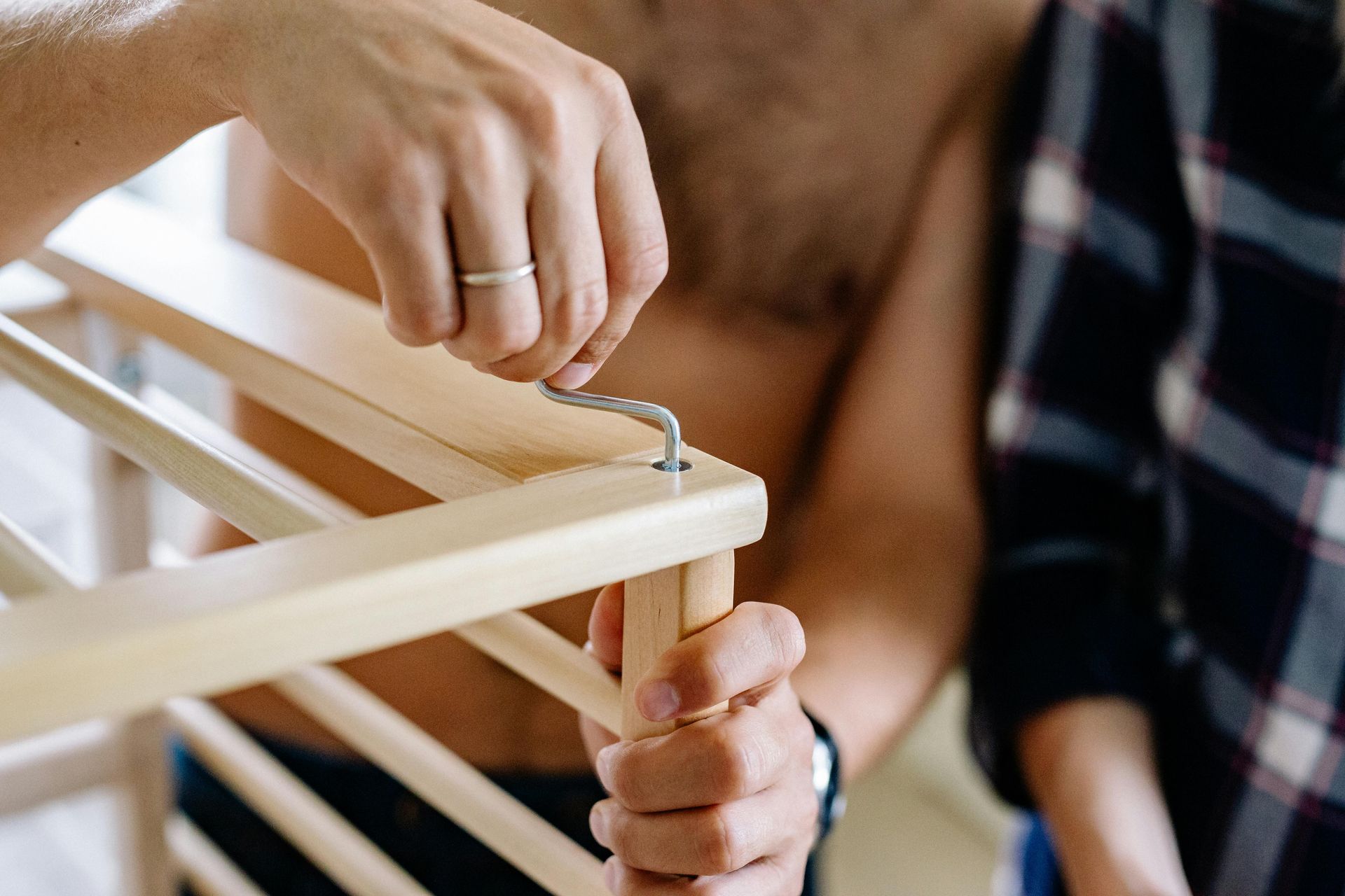 Person attaching hardware to wooden furniture frame.