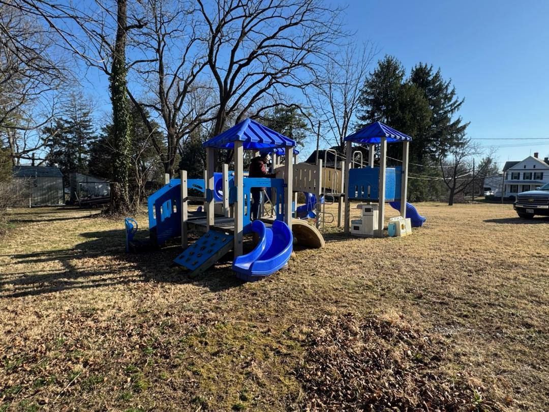 Playground with blue slides and roofs on brown grassy lot.