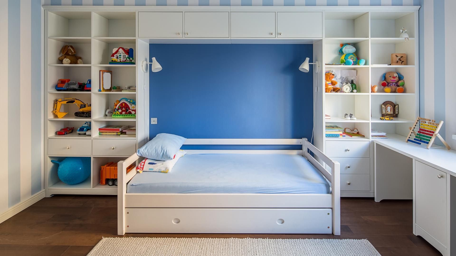 A child 's bedroom with a bed , shelves , and a desk.