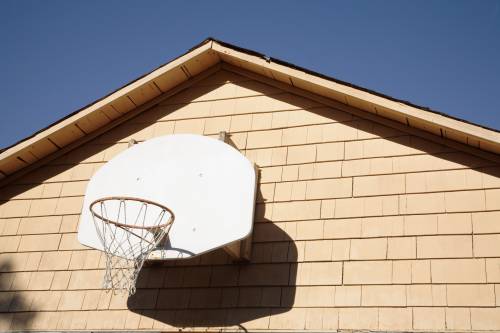 A basketball hoop is attached to the side of a house