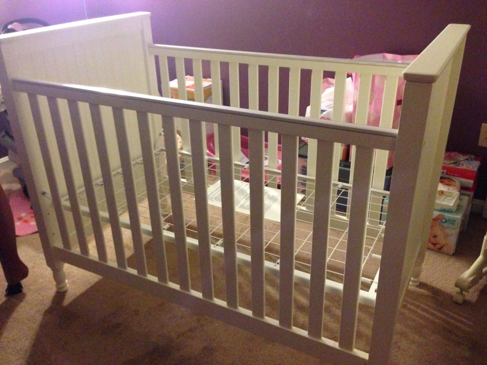 A white crib is sitting on the floor in a room