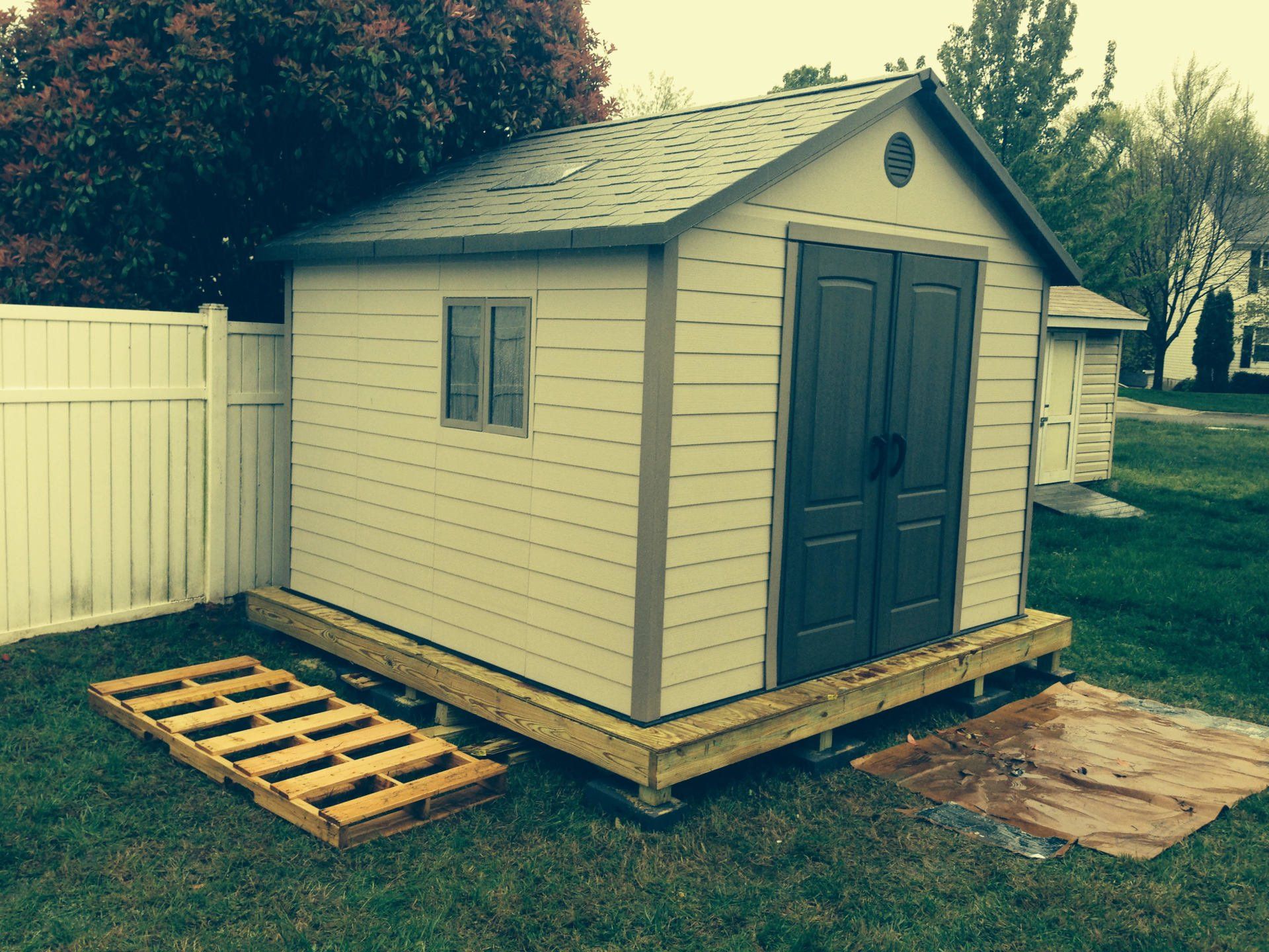 A shed with a wooden deck and pallets in front of it