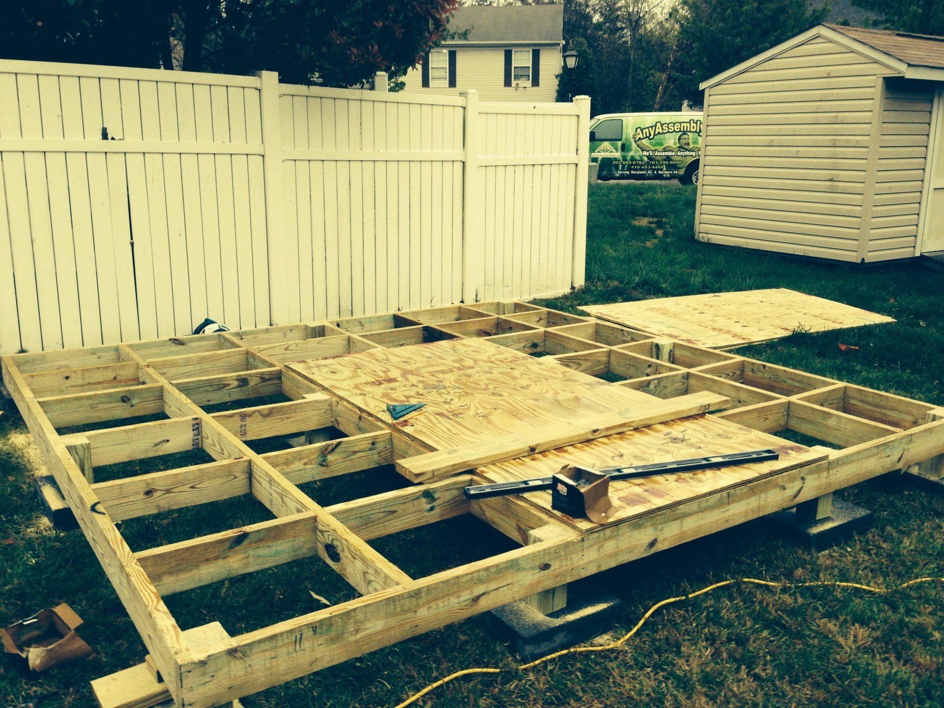 A wooden shed is being built in a backyard