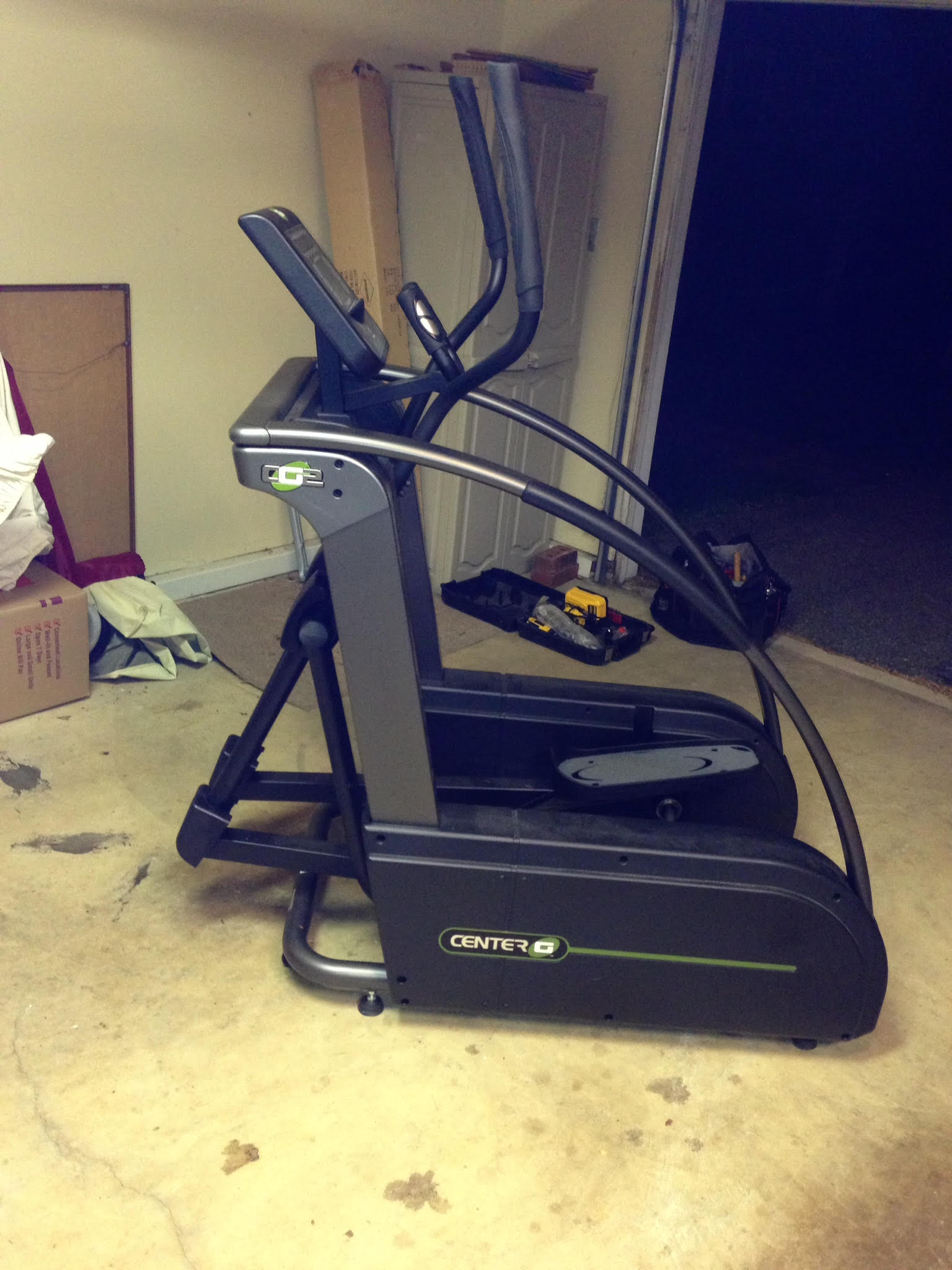An elliptical machine is sitting on the floor in a garage.