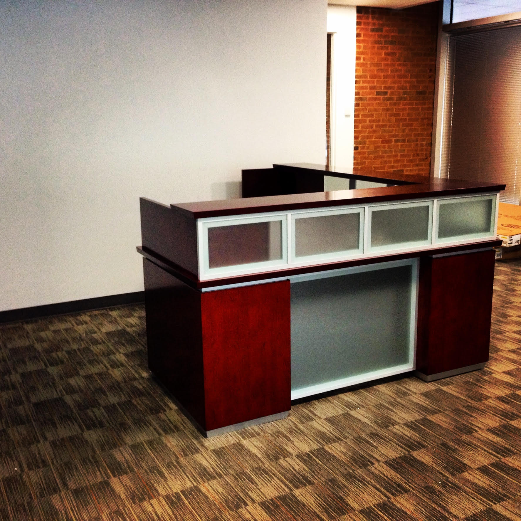 A reception desk in an empty room with a brick wall