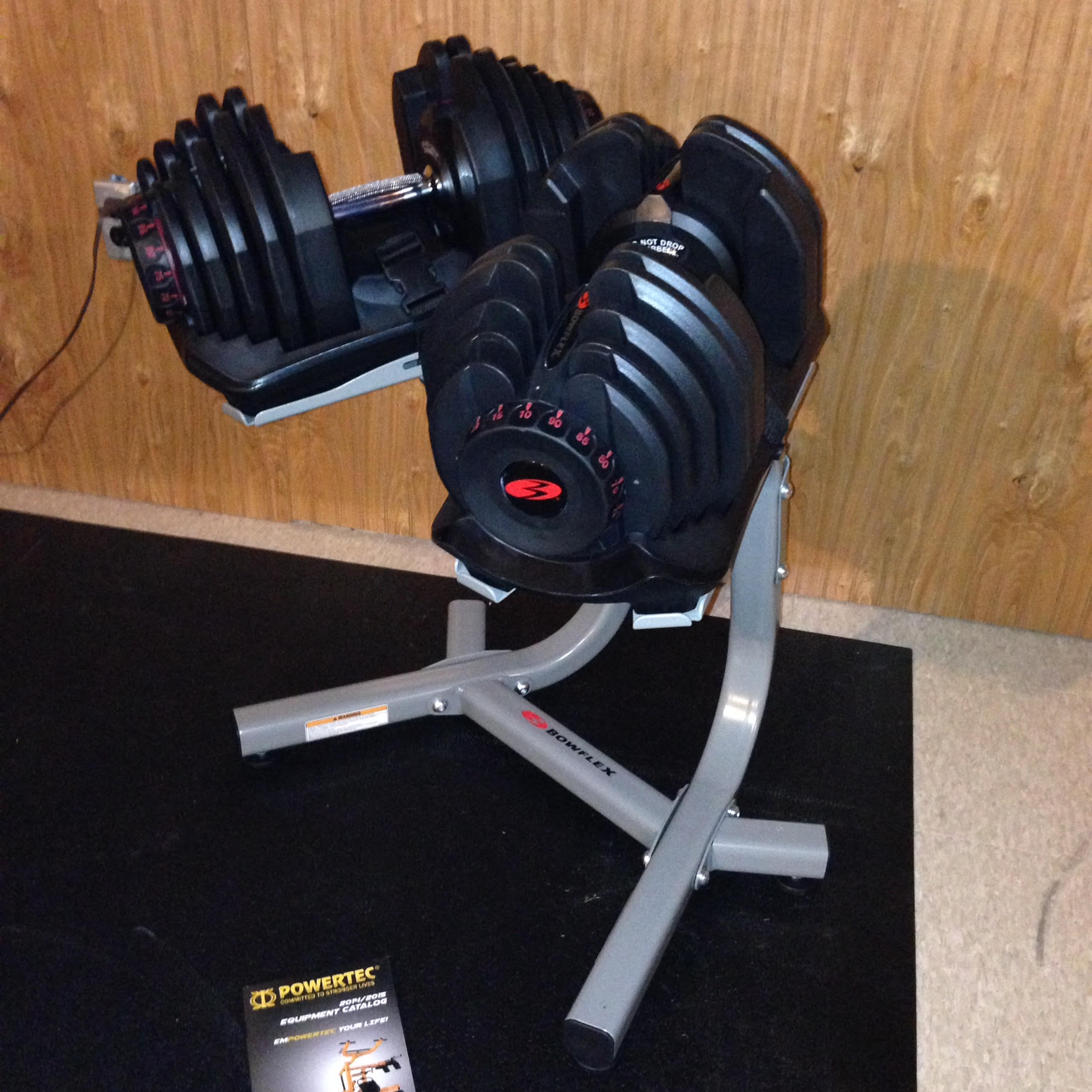A pair of dumbbells on a stand next to a manual