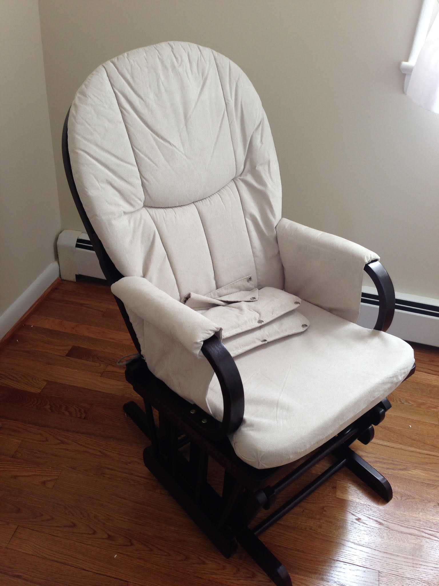 A white rocking chair is sitting on a wooden floor in a room.