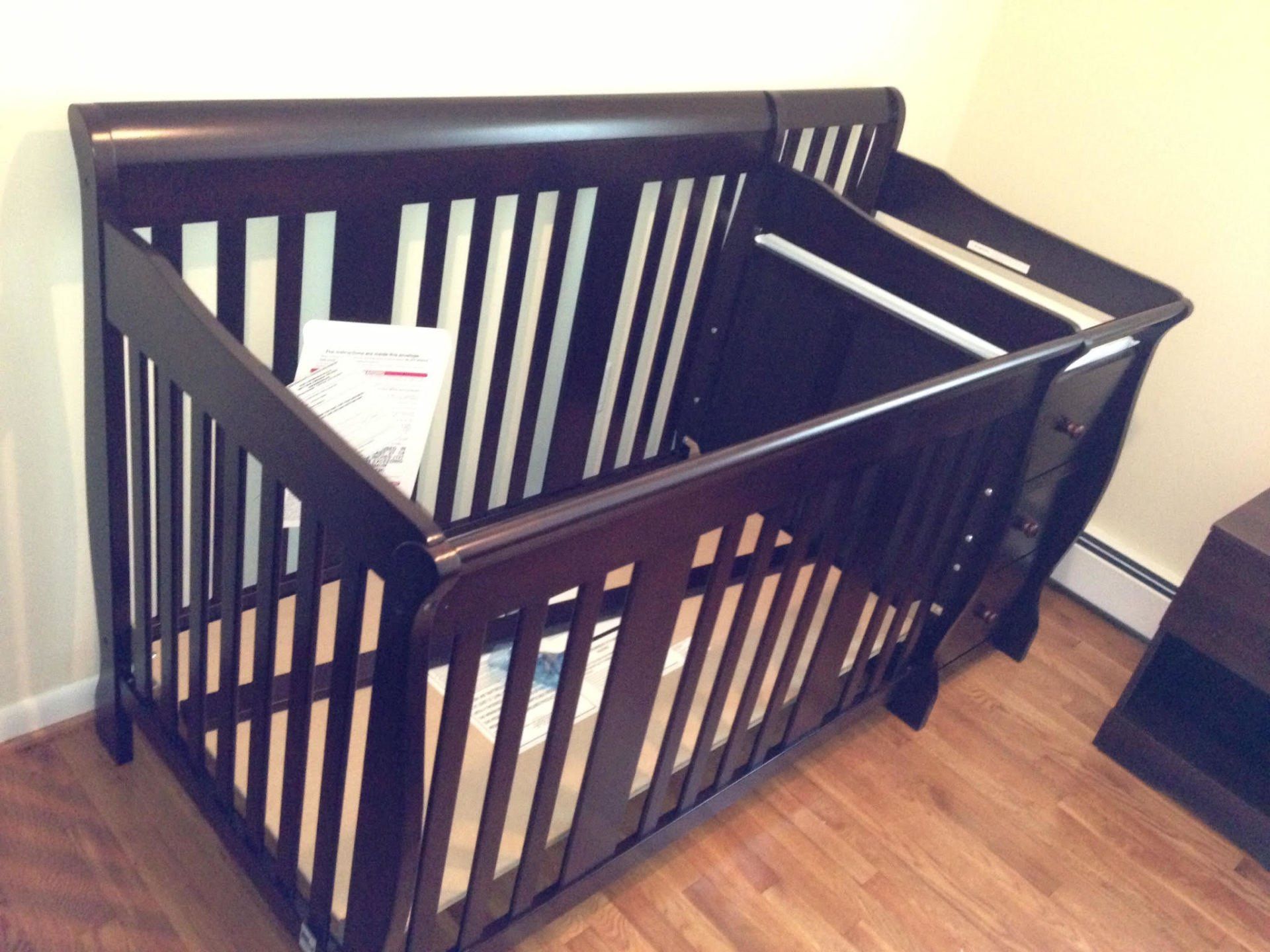 A brown crib is sitting on a wooden floor in a room