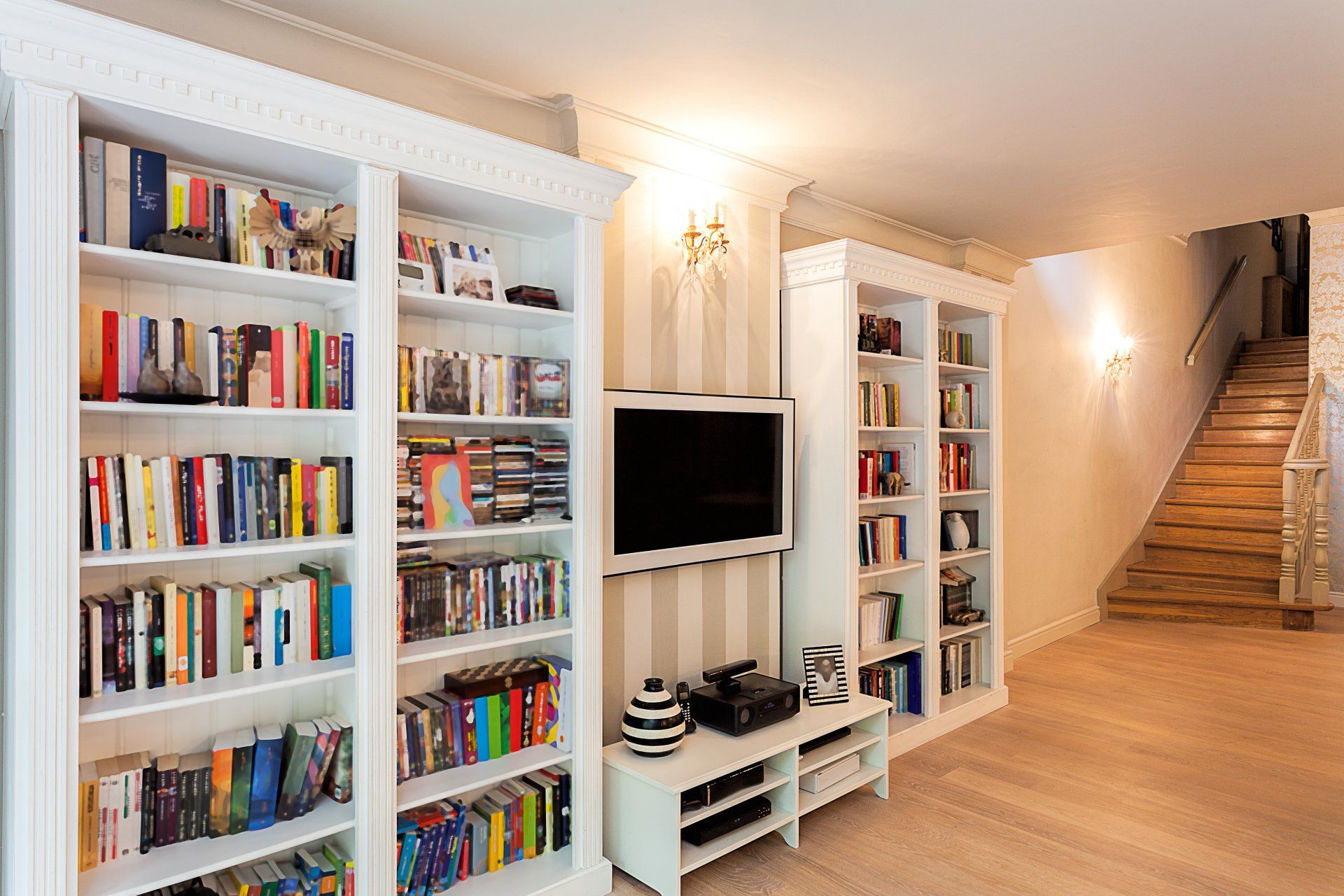A living room filled with lots of books and a flat screen tv.