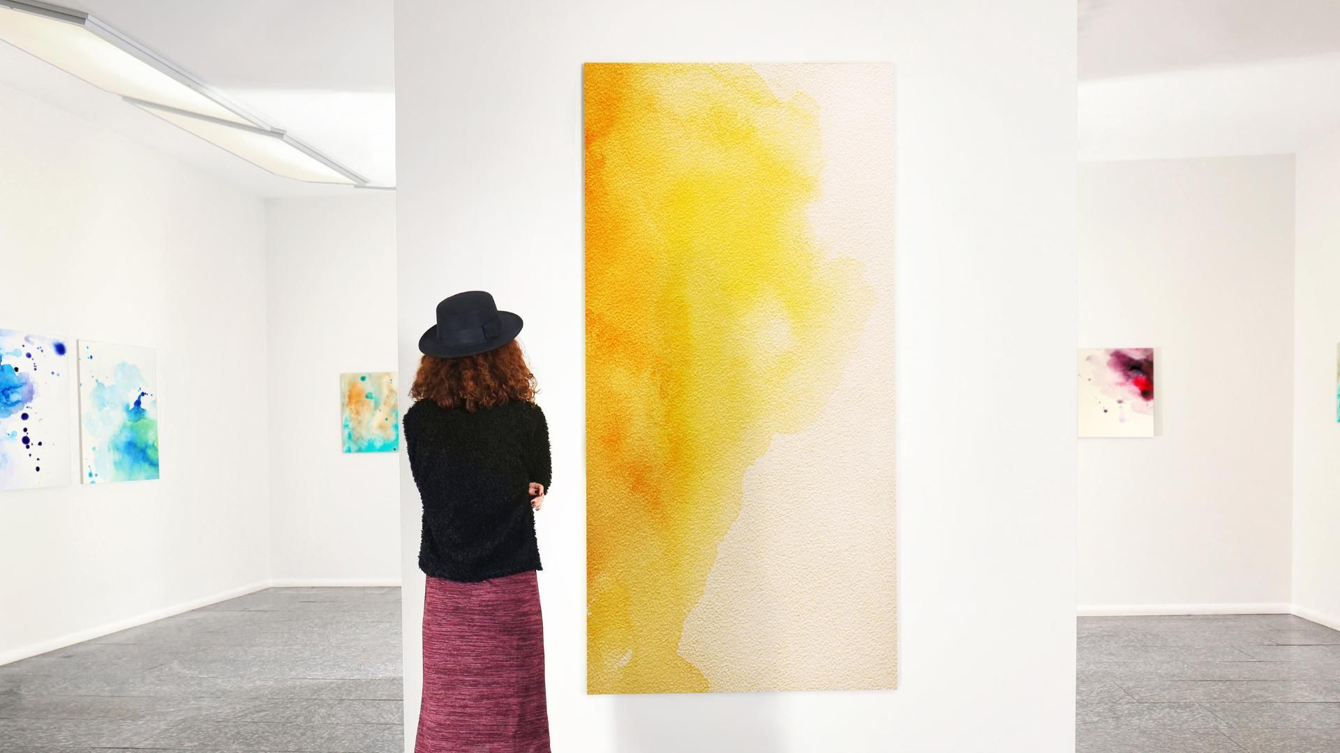 A woman is looking at a painting in a museum.