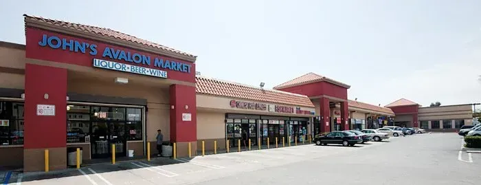 John’s Appliance warehouse storefront in a shopping plaza with glass entrance and parked cars
