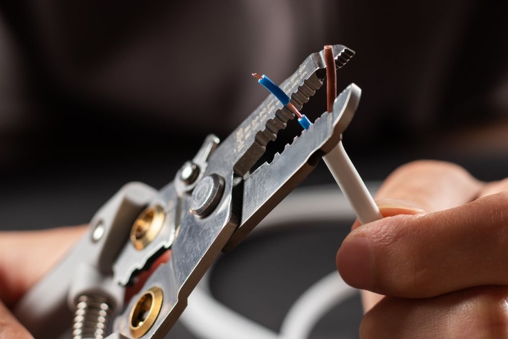 A person is cutting a wire with a pair of pliers.