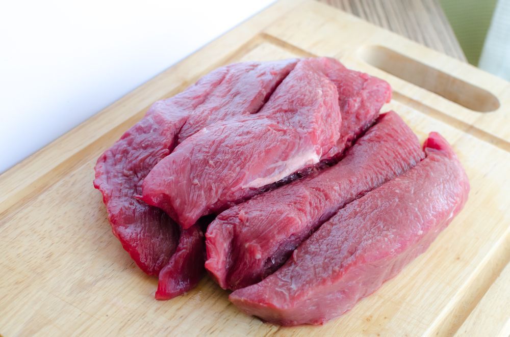 Sliced raw red meat on a wooden cutting board — NQ GAME MEAT in Kirwan, QLD