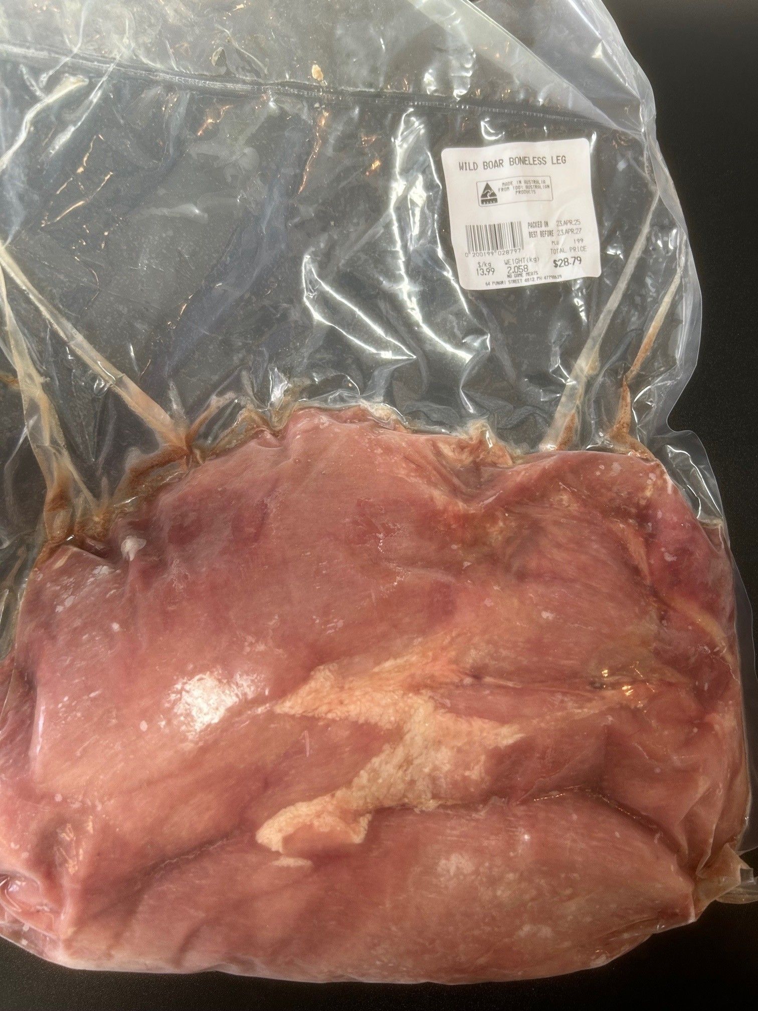 Vacuum-sealed package of raw meat; shades of pink and beige. White label visible on top right — NQ GAME MEAT in Currajong, QLD 