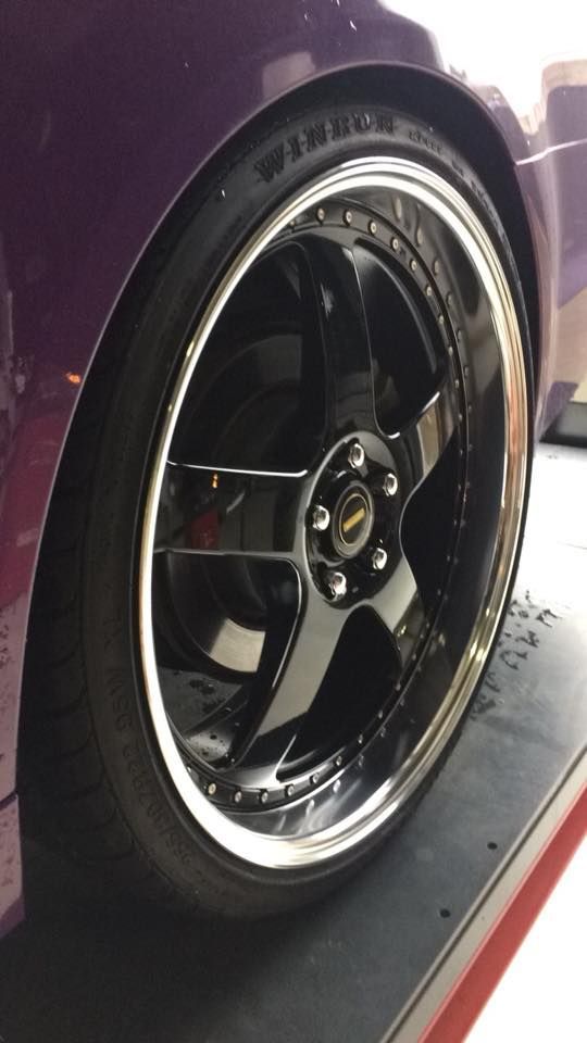 Close-up of a black five-spoke alloy wheel, positioned on a wheel alignment platform.