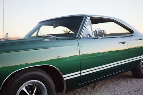 Green classic car with white stripes parked outside.