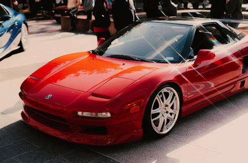 Red Honda NSX sports car, parked, shiny paint, low profile, chrome rims.