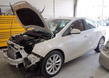 a white car with the hood open is sitting in a garage .