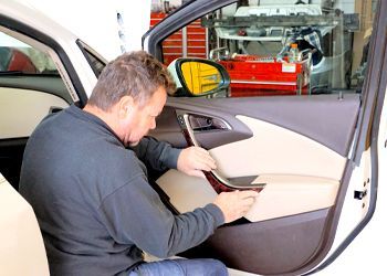 a man is working on the interior of a car in a garage .
