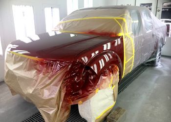 a red truck is being painted in a paint booth .