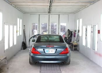 a blue car is parked in a paint booth .