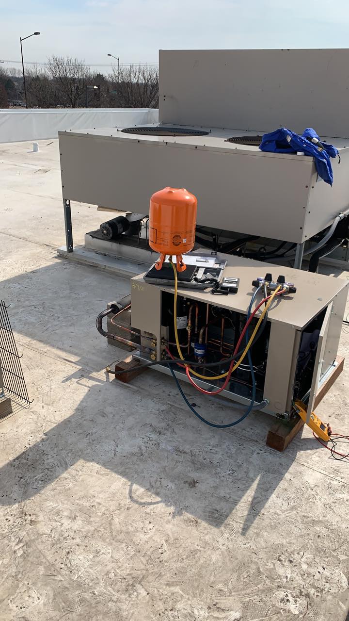 An air conditioner is being repaired on a roof.