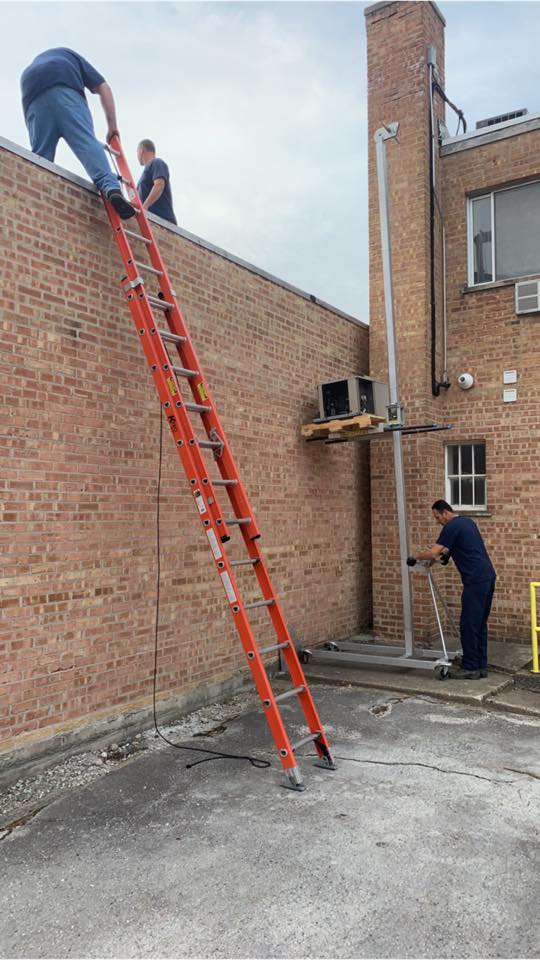 A man is climbing a ladder on the side of a building.