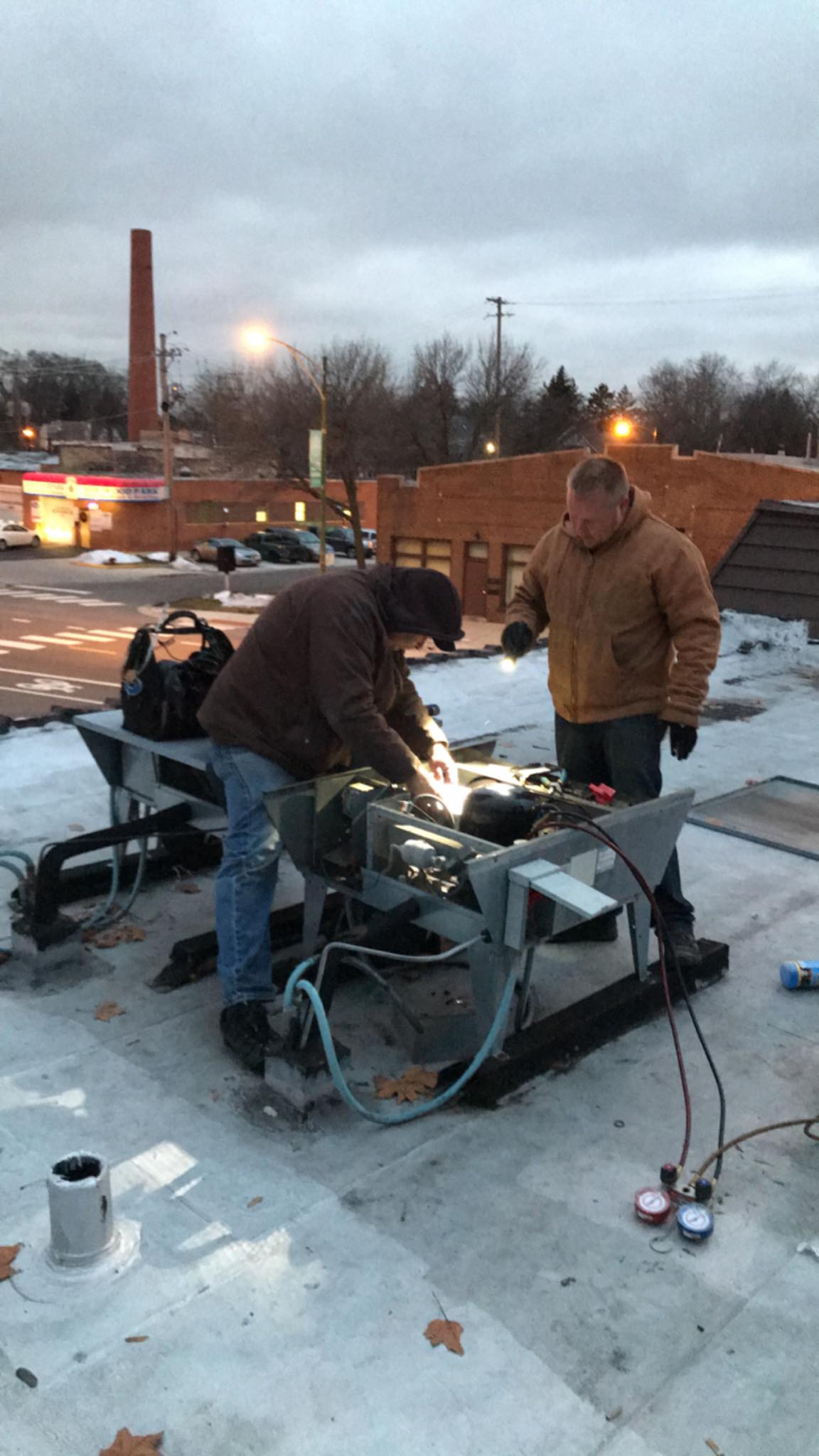 Two men are working on a roof in the snow.