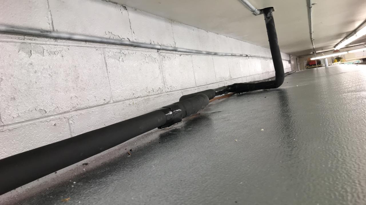 A black pipe is hanging from the ceiling of a building.