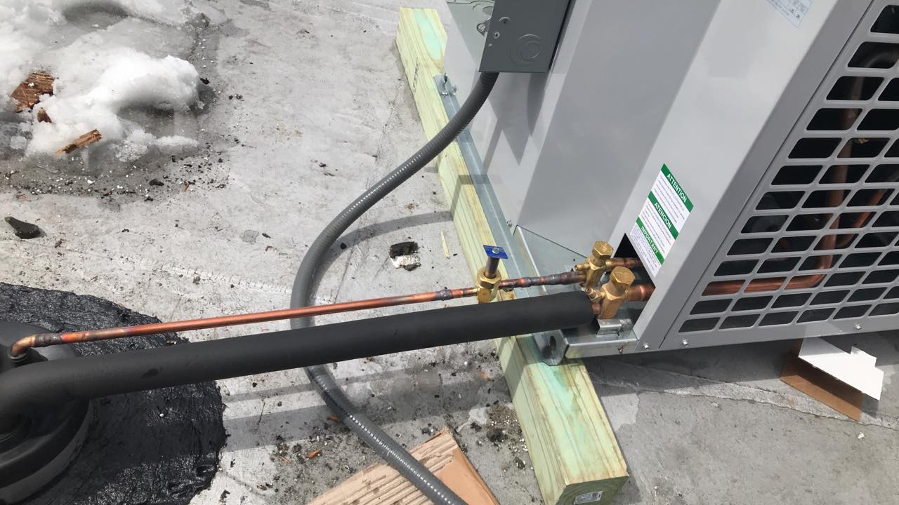 A close up of an air conditioner with a copper pipe attached to it.