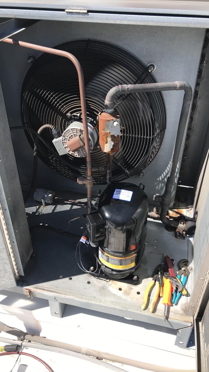 A fan is sitting inside of a building next to a compressor.