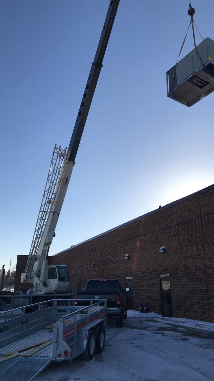A large crane is lifting a large box into a building.