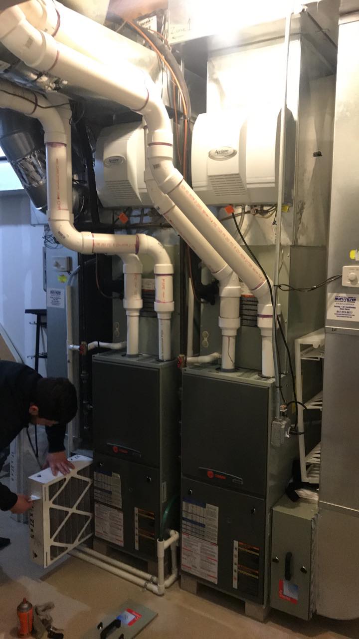 A man is working on a heating system in a basement.