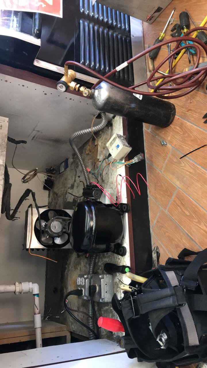 A refrigerator is being repaired in a kitchen.