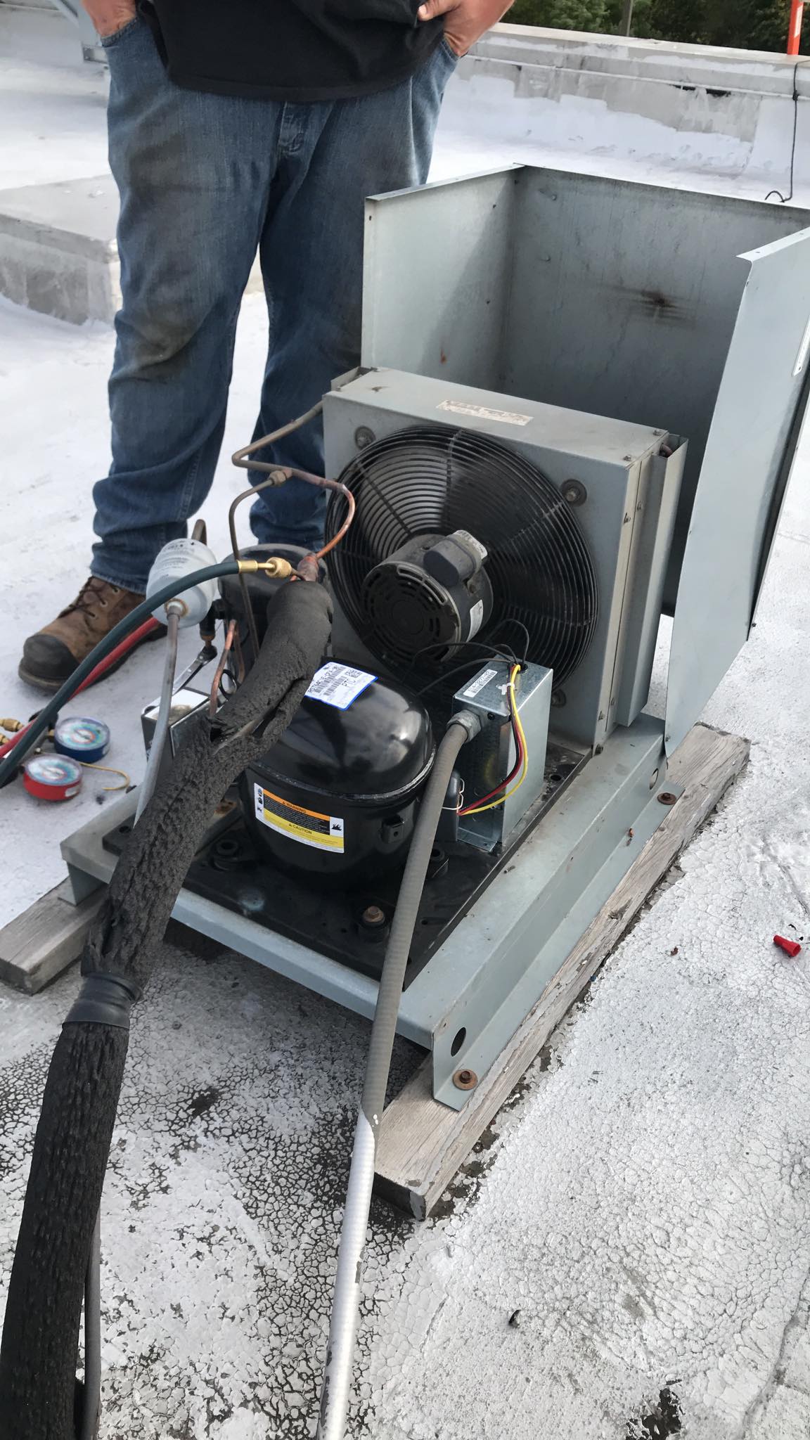 A man is working on an air conditioner on a roof.