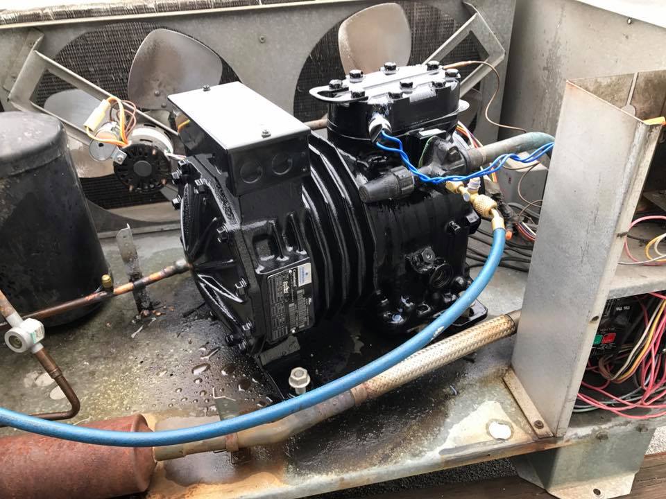 A compressor is sitting on top of a machine with a blue hose attached to it.